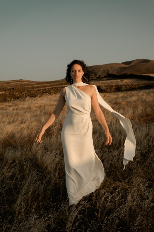 ONDINE est une robe de mariée chic en crêpe de soie. Son décolleté asymétrique en fait une robe de mariée élégante. C’est une robe de mariée drapée féminine pour un mariage cool et chic. Bijoux @anthemis.paris
